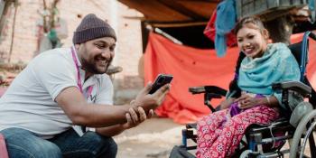 Volunteer laughs with girl in wheelchair